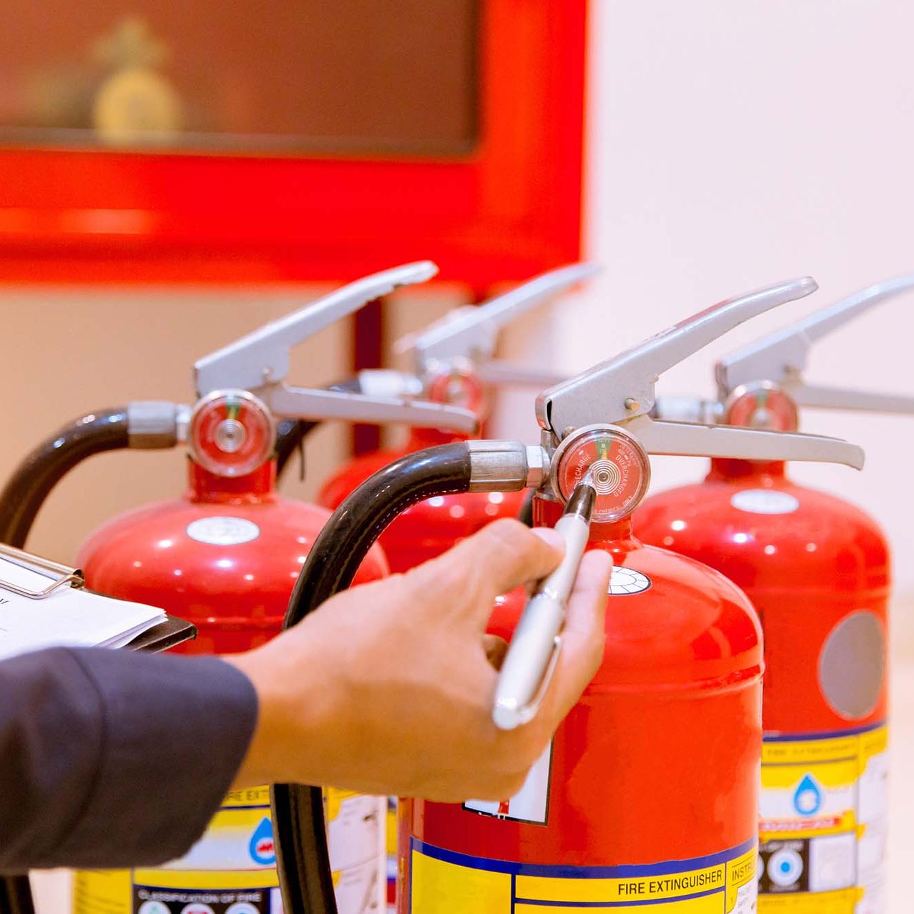 Fire protection engineer check the safety pin of red fire extinguishers tank at the exit door in the building concepts for fire prevention emergency and safety rescue of fire services and training