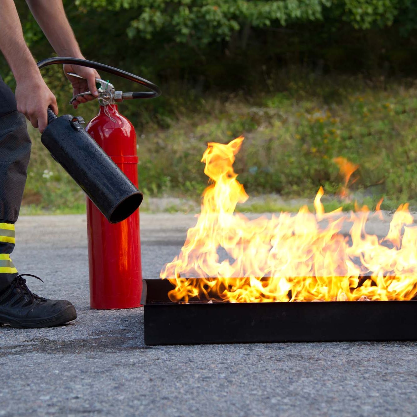 Instructor showing how to use a fire extinguisher on a training fire